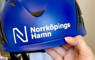 En marinblå skyddshjälm med norrköpings hamns logotyp