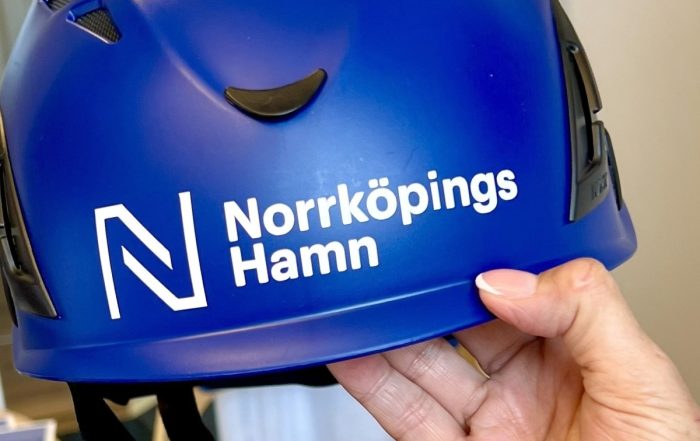 En marinblå skyddshjälm med norrköpings hamns logotyp