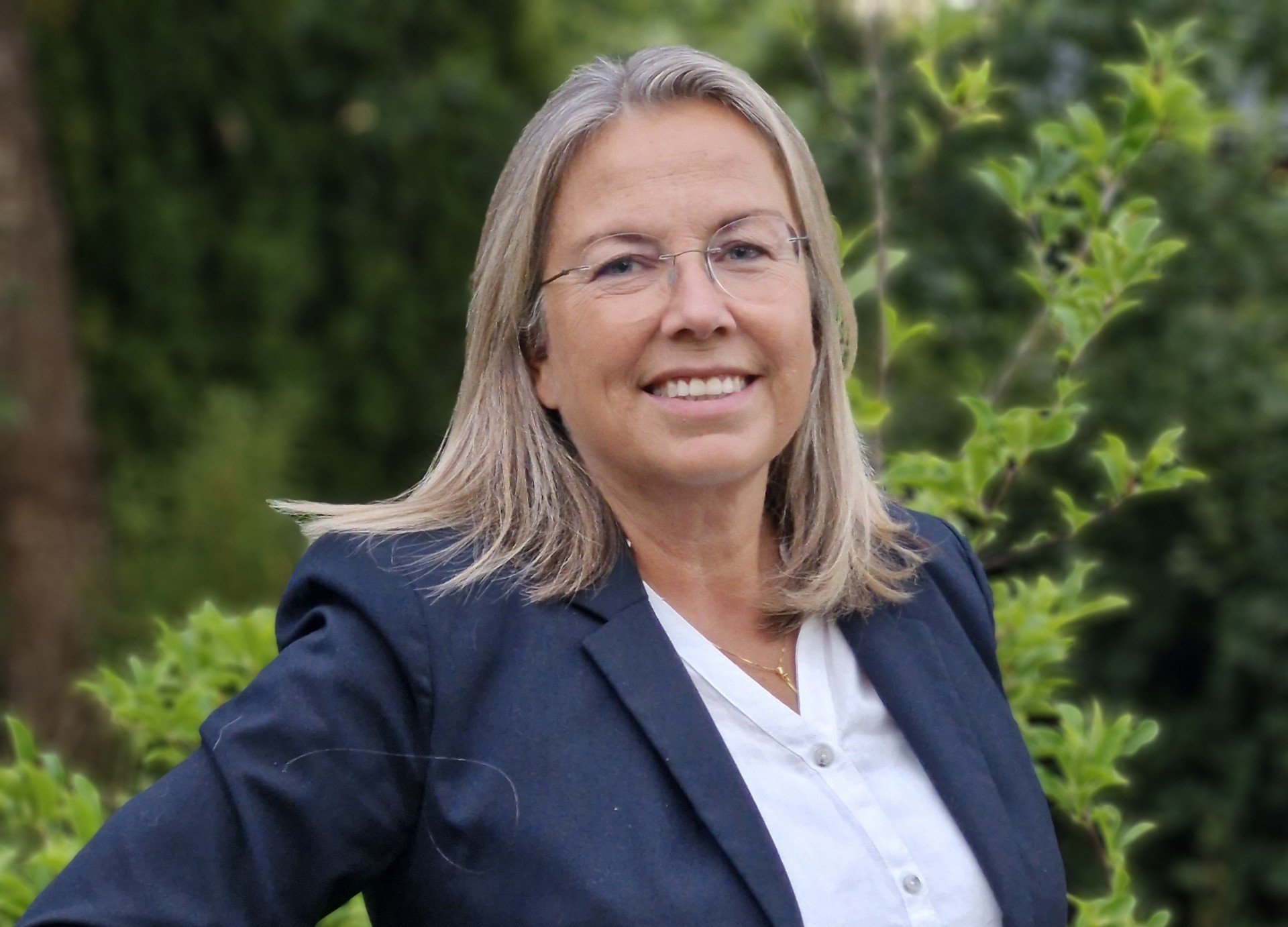 Eva Lindell Eva Lindell, ny vd Norrköpings Hamn, kvinna, leende, i blå kavaj, grön växtlighet i bakgrunden.