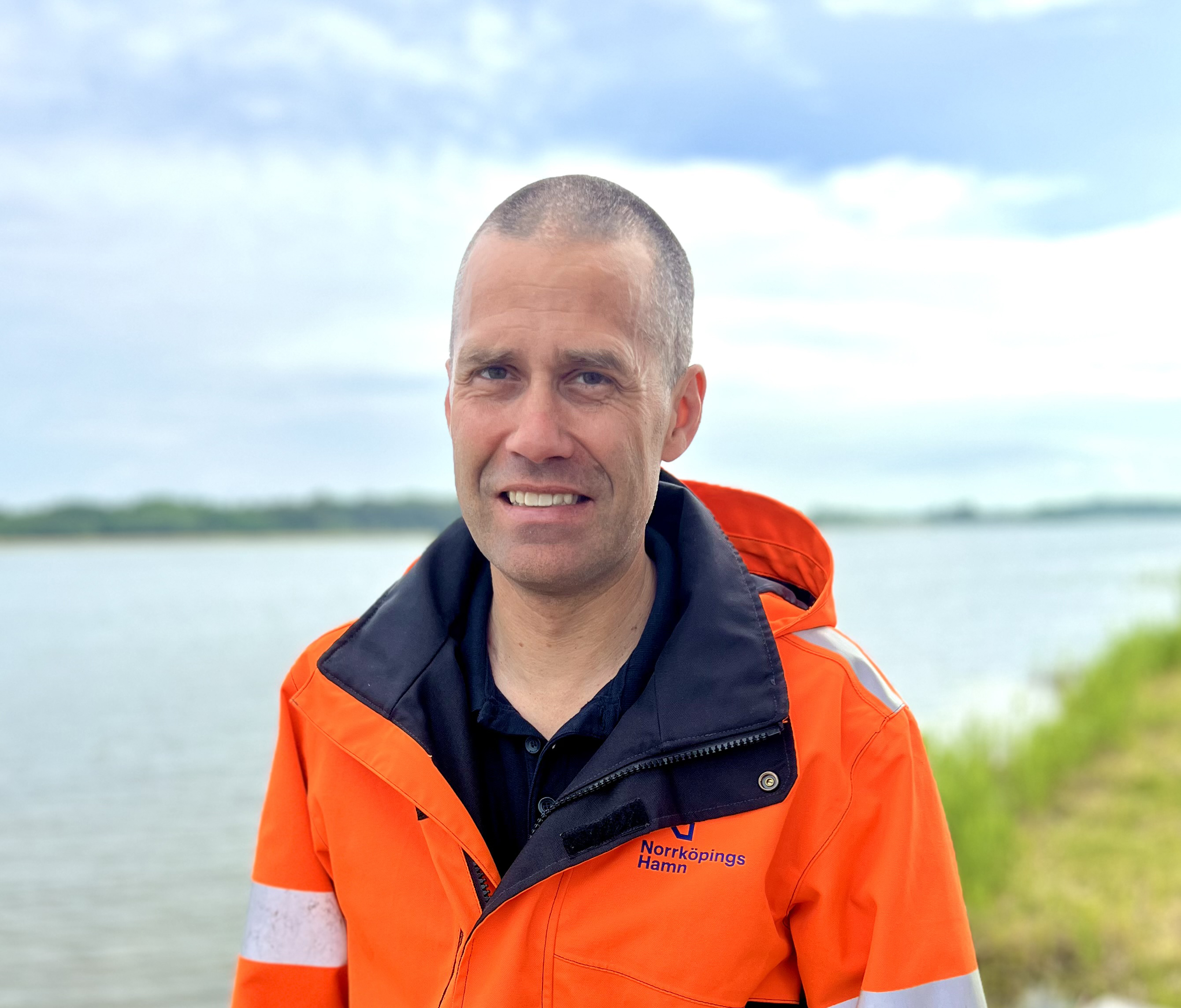 Fredrik Sandberg, ekonomichef, i reflexjacka mot bakgrund av vatten och skog.