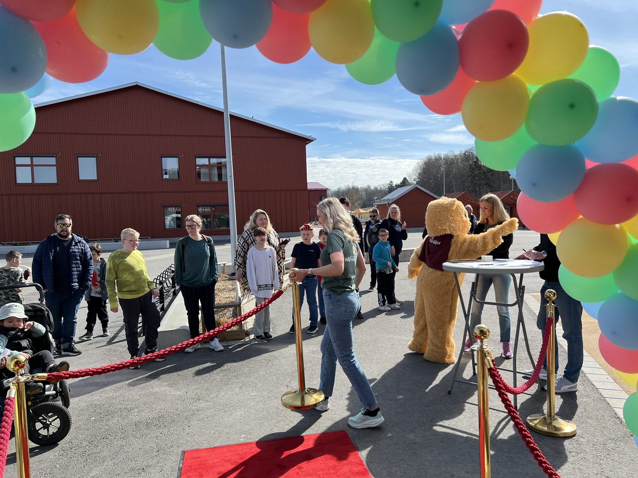 Ballongportal, väntande barn och en person utklädd till björn.