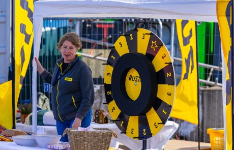 Rustas monter med kvinnlig medarbetare framför ett lyckohjul i gult och svart.