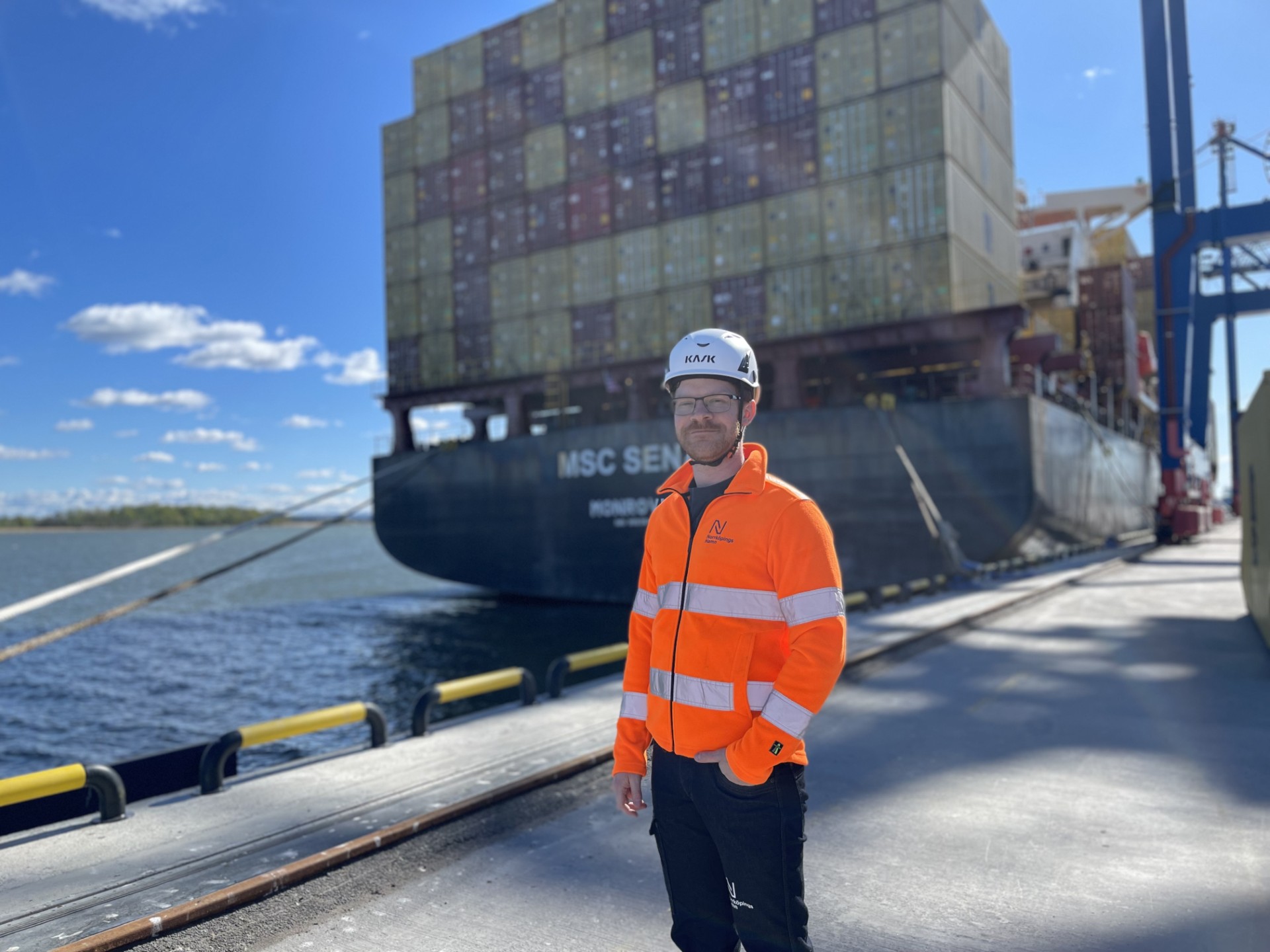 Johannes Sandgren i reflexjacka och hjälm med containerfartyg i bakgrunden.